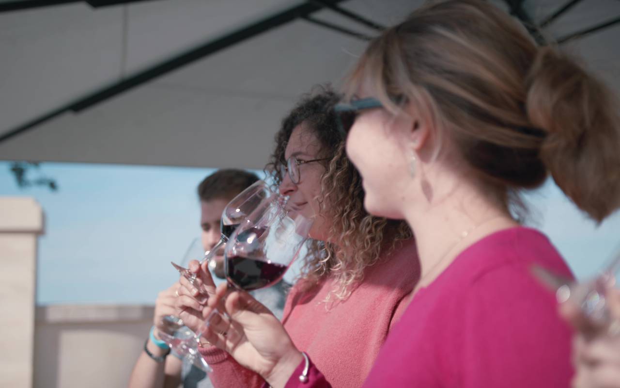 L'image montre trois personnes dégustant du vin dans un hôtel près de Saint-Emilion.