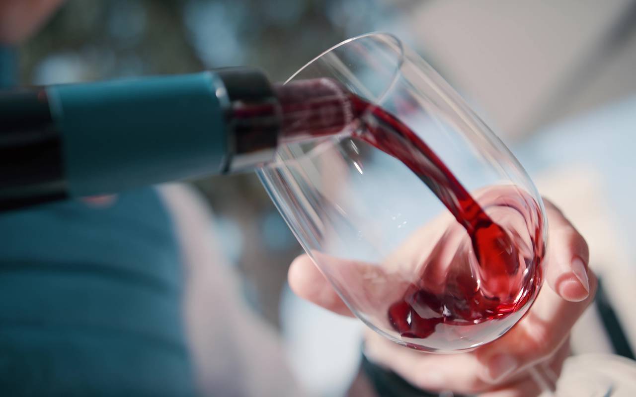 Photo de dégustation de vin dans un hôtel près de Saint-Emilion, gros plan sur le moment de verser le vin dans le verre.